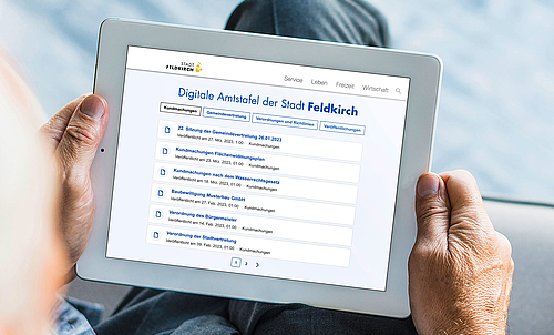 Eine Person hält ein Tablet in den Händen, auf dem Tablet ist das Veröffentlichungsportal der Stadt Feldkirch zu sehen. 