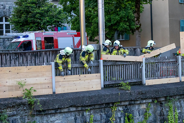 Feuerwehrmänner und -frauen beim Aufbauen des Hochwasserschutzes entlang der Ill.