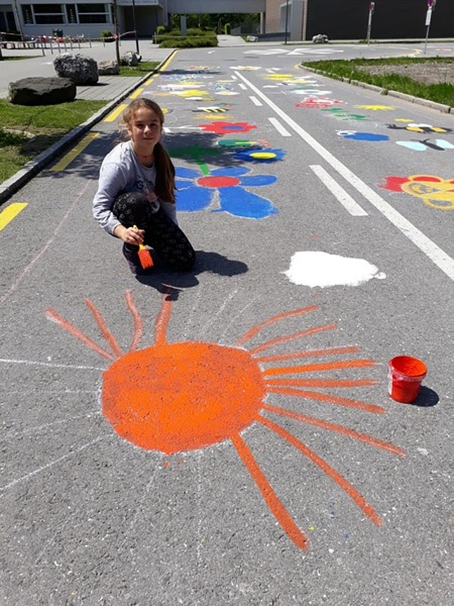 Ein Mädchen malt eine orangefarbene Sonne