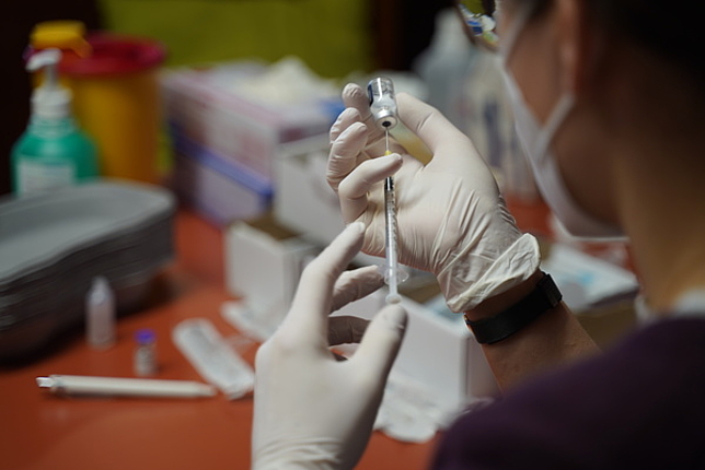 Eine Ärztin hält eine Nadel und eine Impfampulle in der Hand. 