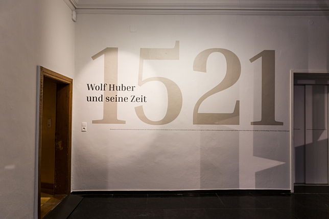 Ein Ausstellungsraum im Palais Liechtenstein mit dem Schriftzug an der Wand: 1521 - Wolf Huber und seine Zeit