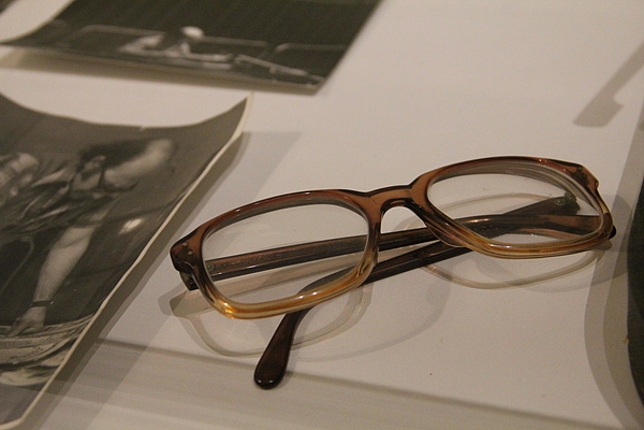 Brille liegt neben Fotos auf einem Schreibtisch.