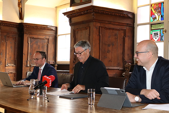 Finanzstadtrat Benedikt König, Bürgermeister Wolfgang Matt und Stadtkämmerer Bernhard Grabher sitzen im Ratssaal nebeneinander. Vor dem Bürgermeister steht ein Mikrofon des ORF.
