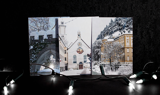 Drei Weihnachtskarten nebeneinander mit Feldkircher Motiven, vor den Karten liegt eine Lichterkette