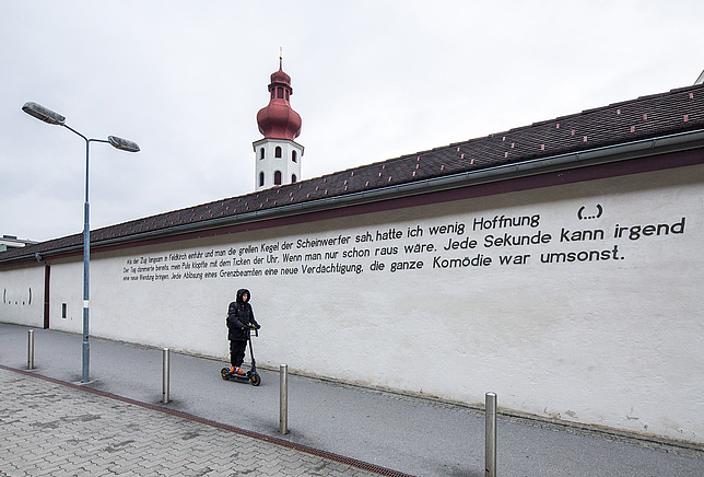 Mauer am Bahnhof Feldkirch an dem ein Zitat zu lesen ist. 