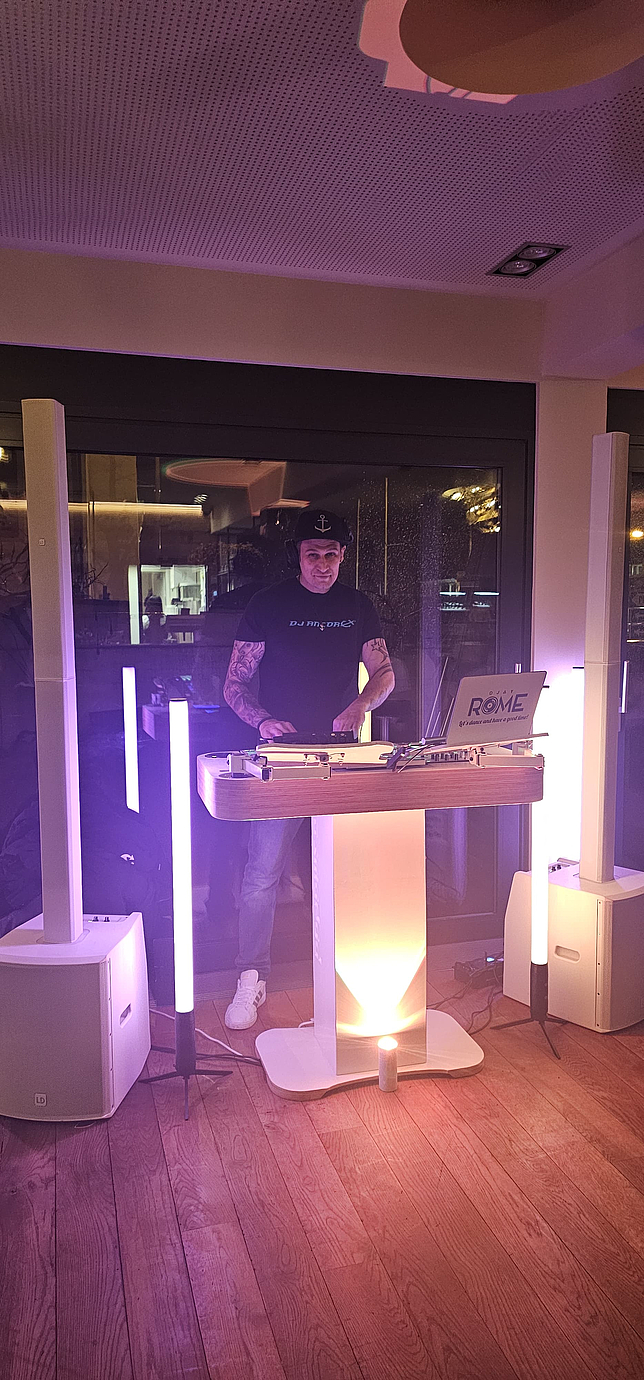 Ein Mann steht an einem DJ-Mischpult.