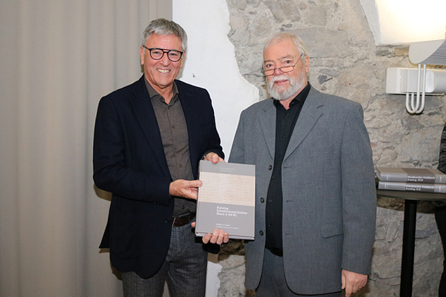 Bürgermeister Wolfgang Matt mit Manfred Getzner, sie halten ein Buch in ihren Händen.