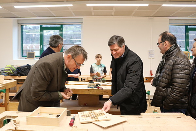 Wirtschaftsbund Direktor Christoph Thoma und Vizebürgermeister Daniel Allgäuer begutachten ein Holz-Werkstück, ein selbstgemachtes "Mensch-Ärger-Dich-Nicht"-Spielbrett.