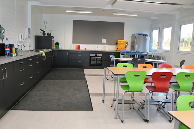 Küche in der Modul-Erweiterung der Volksschule Nofels, neben der Küche stehen noch Tische und Stühle