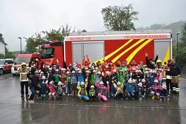 Eine Gruppe von Kindern steht mit Feuerwehrleuten vor einem Feuerwehrauto.