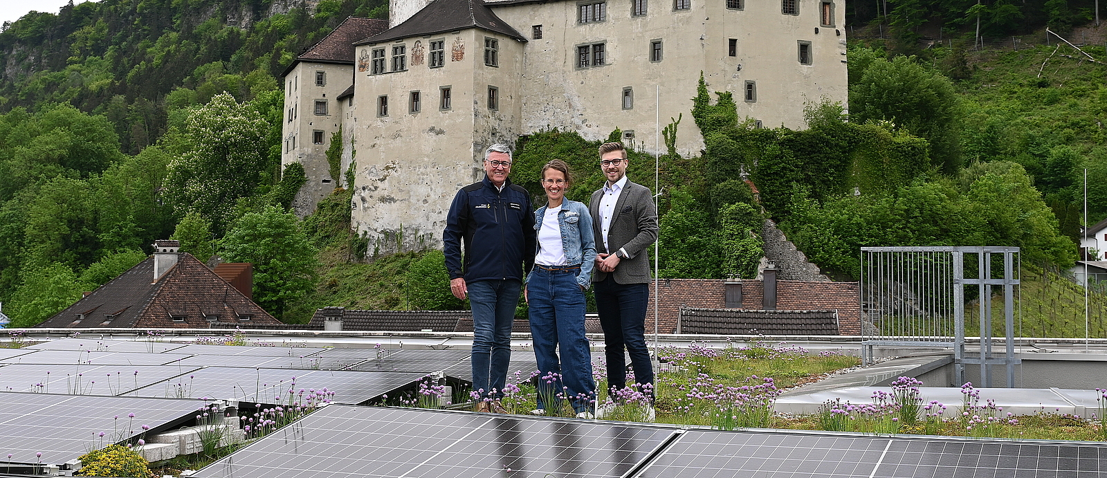 Bürgermeister Wolfgang Matt, Stadtrat Wolfgang Flach und die städtische Mitarbeiterin Christina Connert stehen auf dem Dach des Montforthauses. Hinter ihnen ist die Schattenburg zu sehen. 