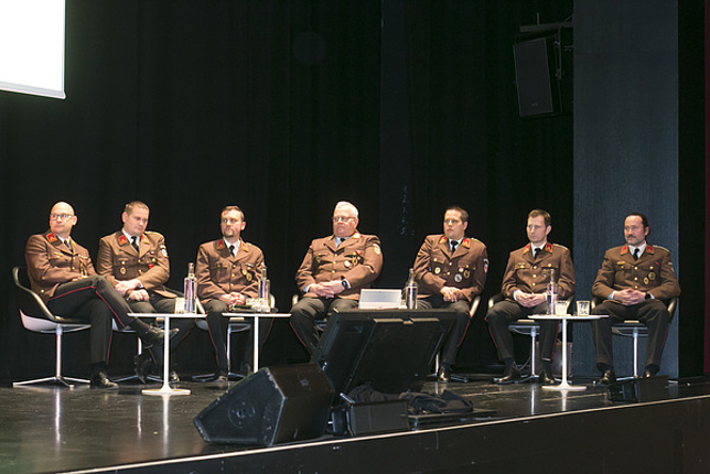 Die Kommandanten aller Feuerwehren und Katastrophenschutzbeauftragter Josef Fröhlich sitzen auf Stühlen auf der Bühne