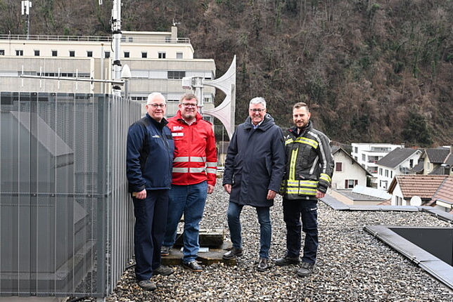 Josef Fröhlich (Katastrophenschutzbeauftragter), Christoph Kaar (Rotes Kreuz), Bürgermeister Wolfgang Matt und Marcel Frick (Feuerwehr Altenstadt) stehen auf dem Dach der Rettungsabteilung neben der neuen Sirene.