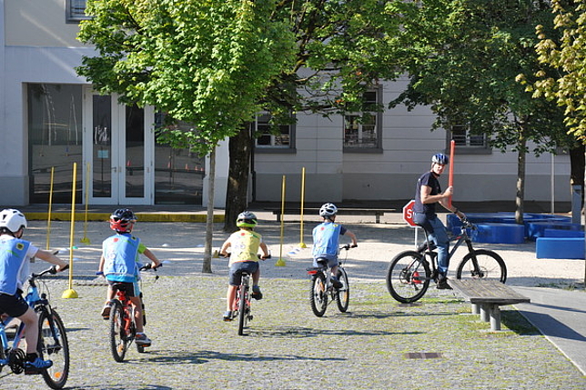 Kinder fahren einem Herr auf dem Fahrrad hinterher.