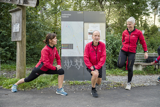 Zwei Frauen und ein Herr des Laufsportvereins Feldkirch dehnen sich.
