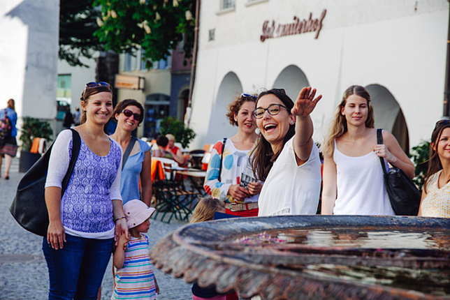 Eine Stadtführerin erklärt einer Gruppe von Menschen etwas in der Marktgasse in Feldkirch. 