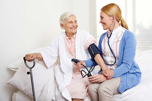 Eine Pflegerin misst bei einer älteren Dame den Blutdruck.